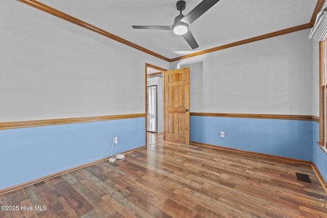 unfurnished room featuring baseboards, visible vents, ornamental molding, and wood finished floors