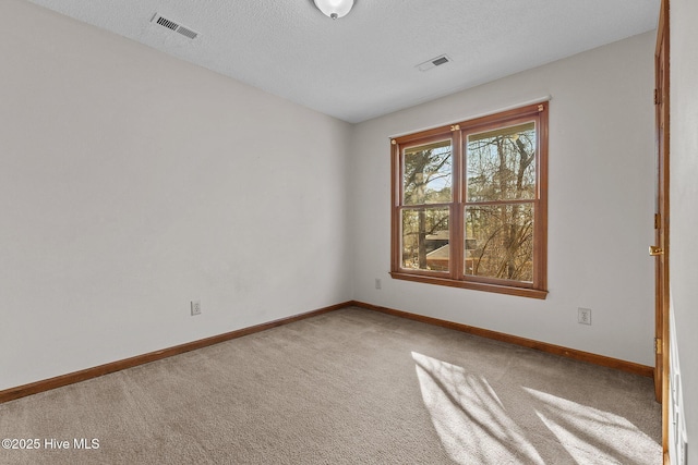 carpeted spare room featuring visible vents, a textured ceiling, and baseboards