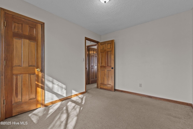 carpeted spare room with baseboards and a textured ceiling