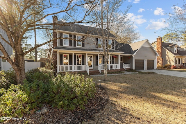 colonial home with driveway, a chimney, an attached garage, covered porch, and fence