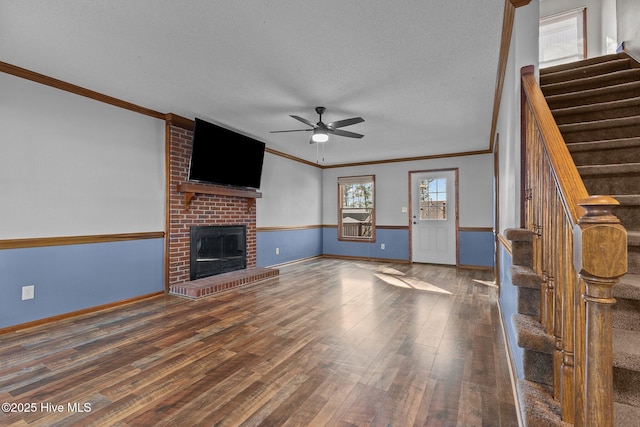 unfurnished living room featuring ornamental molding, stairway, a fireplace, and wood finished floors