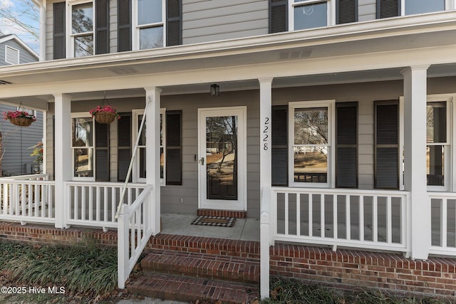 entrance to property featuring covered porch and brick siding