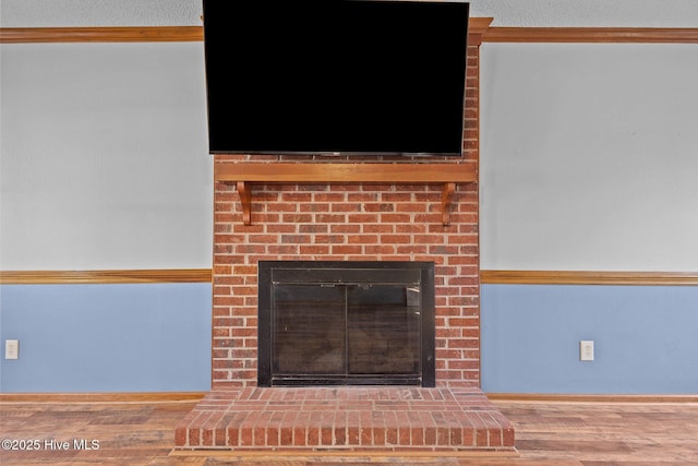 details featuring a brick fireplace, baseboards, and wood finished floors