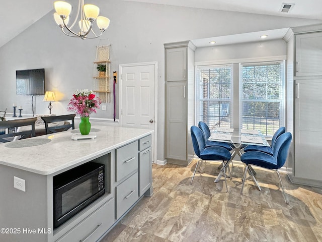 kitchen with gray cabinets, a kitchen island, decorative light fixtures, lofted ceiling, and an inviting chandelier