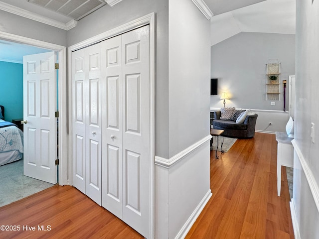 hallway featuring ornamental molding, lofted ceiling, and light hardwood / wood-style flooring