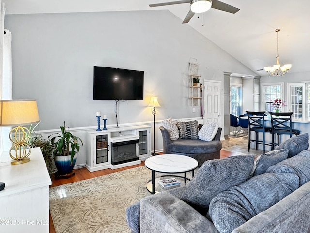 living room with ceiling fan with notable chandelier, lofted ceiling, and hardwood / wood-style floors