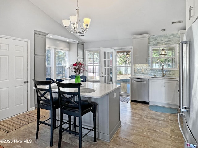 kitchen with hanging light fixtures, gray cabinets, sink, and appliances with stainless steel finishes