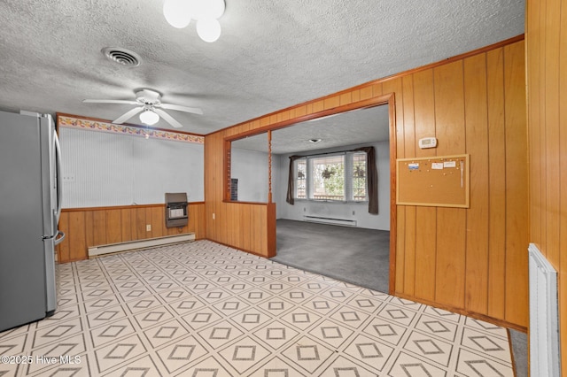 kitchen featuring light carpet, a baseboard heating unit, stainless steel fridge, and wooden walls