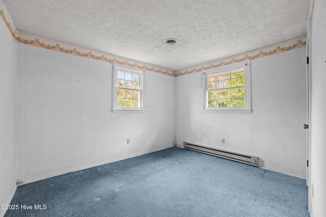 carpeted empty room with a healthy amount of sunlight, a baseboard heating unit, and a textured ceiling