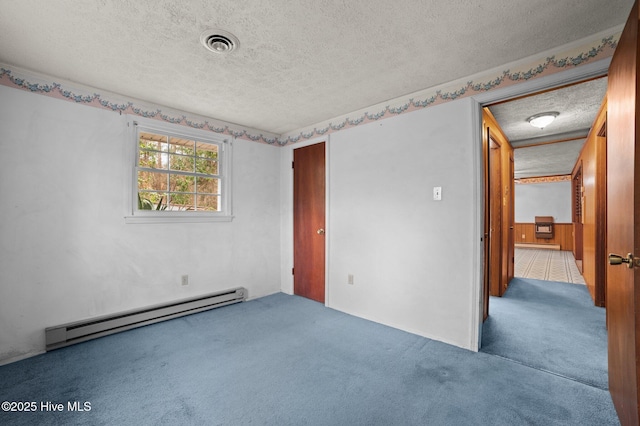 carpeted empty room featuring a baseboard radiator and a textured ceiling