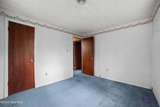 carpeted empty room with a textured ceiling