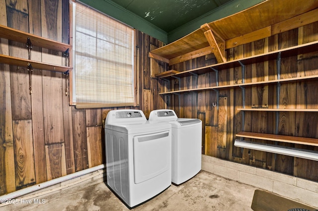 clothes washing area featuring washer and dryer and wood walls