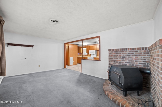 unfurnished living room featuring sink, carpet floors, a textured ceiling, and a wood stove