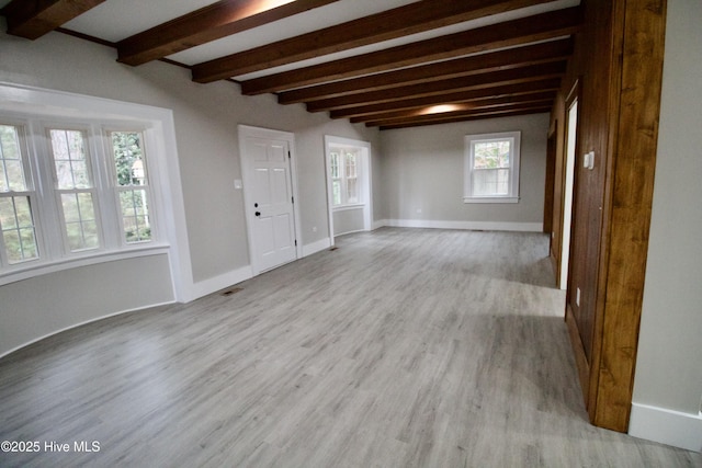 spare room with beam ceiling and light hardwood / wood-style floors