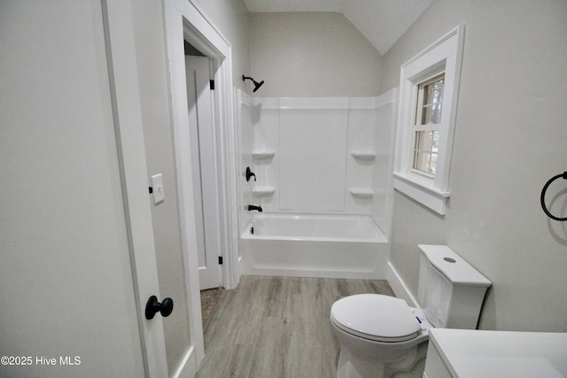 bathroom with toilet, lofted ceiling, wood-type flooring, and shower / washtub combination