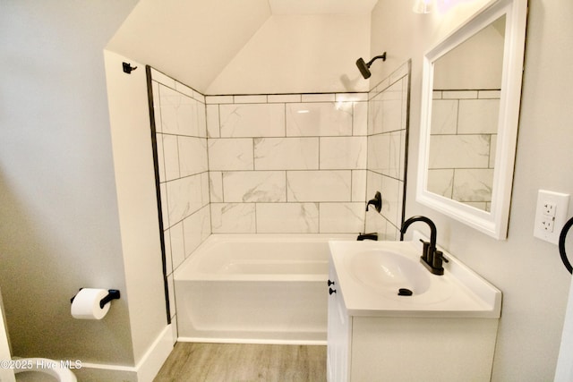 bathroom with tiled shower / bath, wood-type flooring, vanity, and lofted ceiling