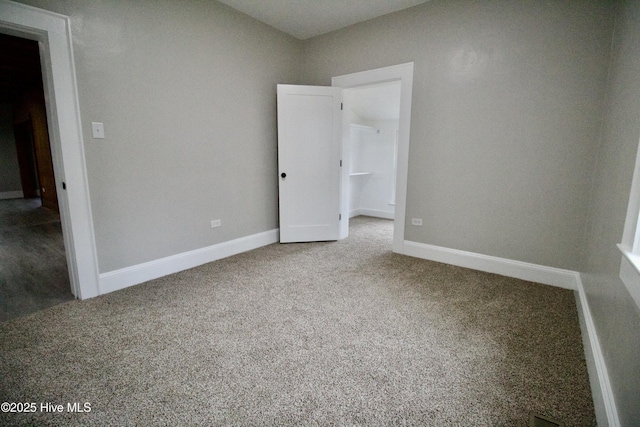 unfurnished bedroom with a spacious closet and carpet