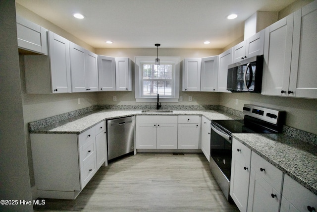 kitchen with sink, hanging light fixtures, white cabinets, and appliances with stainless steel finishes