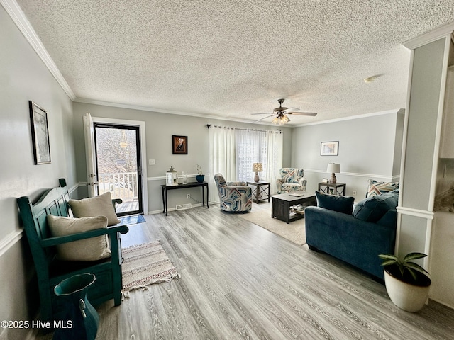 living room featuring ceiling fan, hardwood / wood-style flooring, ornamental molding, and a textured ceiling