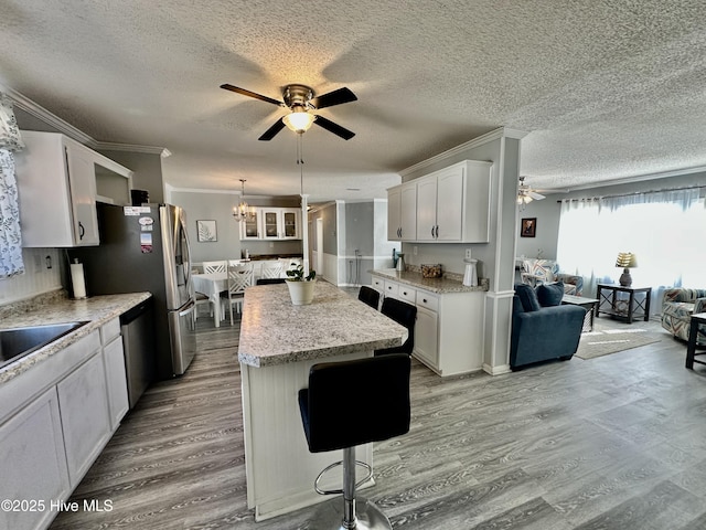 kitchen featuring dishwasher, white cabinetry, hanging light fixtures, a center island, and ceiling fan with notable chandelier