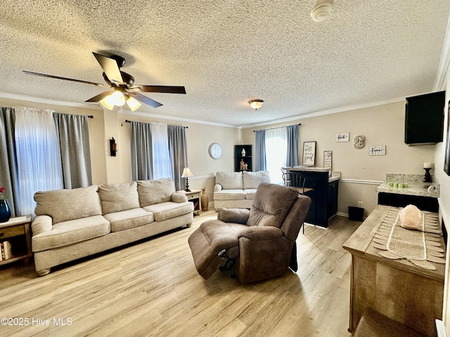 living room featuring crown molding, ceiling fan, a textured ceiling, and light hardwood / wood-style floors