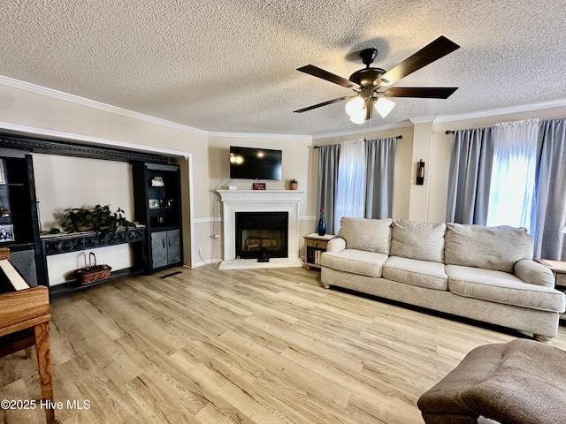 living room with ornamental molding, light hardwood / wood-style floors, and a textured ceiling