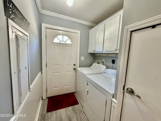 washroom featuring crown molding, cabinets, a textured ceiling, washer and clothes dryer, and light hardwood / wood-style floors