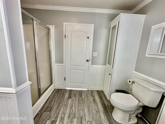 bathroom with walk in shower, toilet, crown molding, and hardwood / wood-style flooring