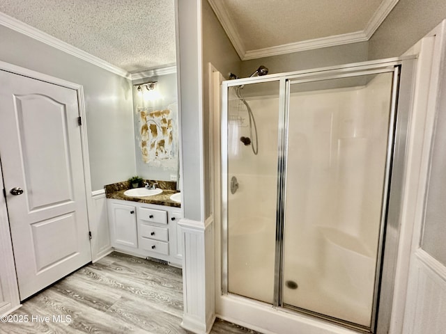 bathroom with hardwood / wood-style flooring, vanity, crown molding, and a textured ceiling