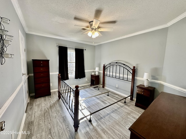 bedroom with crown molding, ceiling fan, a textured ceiling, and light wood-type flooring