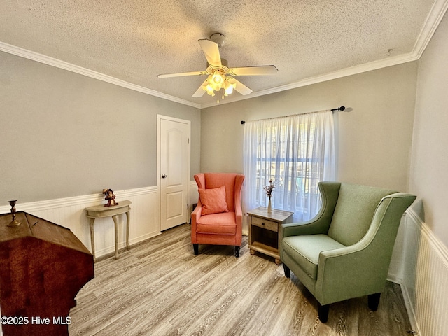 sitting room featuring ornamental molding, a textured ceiling, ceiling fan, and light hardwood / wood-style flooring