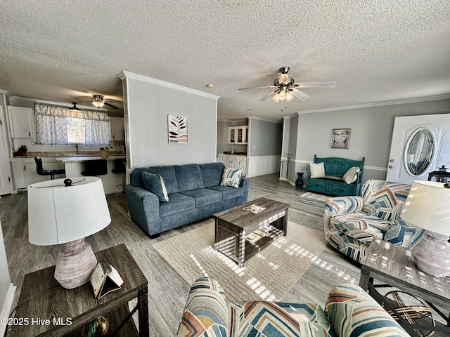 living room featuring wood-type flooring, a textured ceiling, ceiling fan, and crown molding