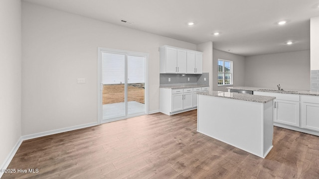 kitchen with a center island, light stone countertops, sink, and white cabinets