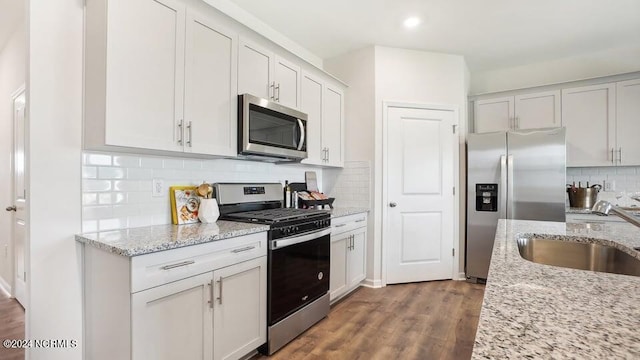 kitchen with light stone countertops, stainless steel appliances, sink, and white cabinets