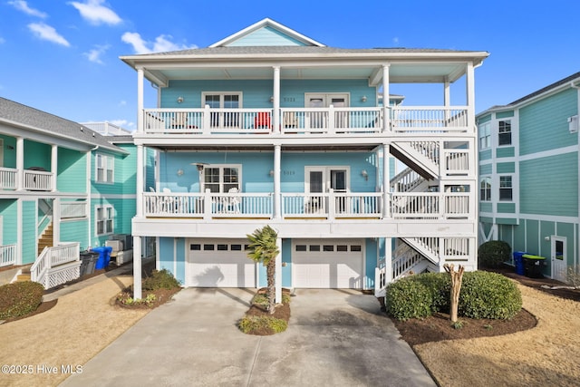 coastal home with driveway, an attached garage, and stairs