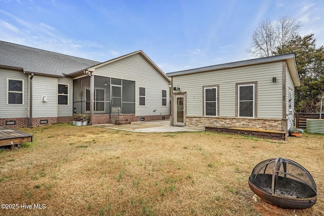 rear view of house with an outdoor fire pit, a yard, a patio area, and a sunroom