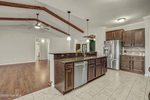 kitchen with appliances with stainless steel finishes, sink, dark stone countertops, hanging light fixtures, and dark brown cabinets