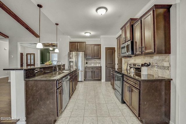 kitchen featuring sink, dark stone countertops, hanging light fixtures, backsplash, and stainless steel appliances