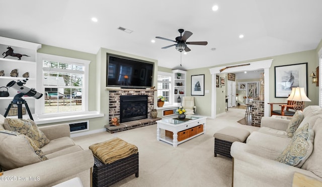 living room with ceiling fan, a fireplace, light carpet, and a wealth of natural light