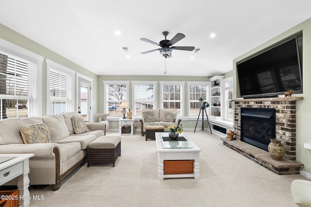 carpeted living room with a brick fireplace and ceiling fan