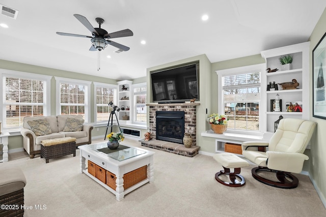 carpeted living room with a brick fireplace and ceiling fan