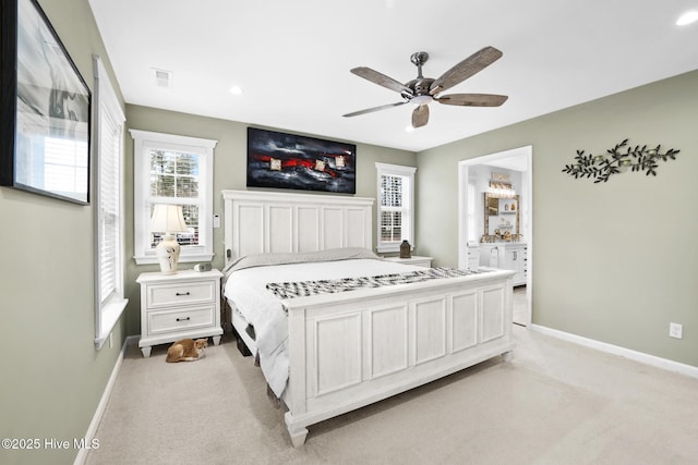 bedroom with ensuite bath, light colored carpet, and ceiling fan