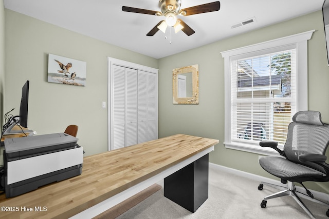 carpeted office space featuring plenty of natural light and ceiling fan