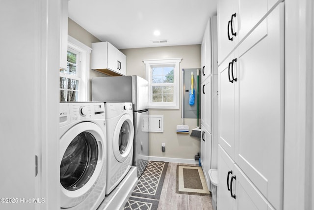 washroom with separate washer and dryer, plenty of natural light, cabinets, and wood-type flooring