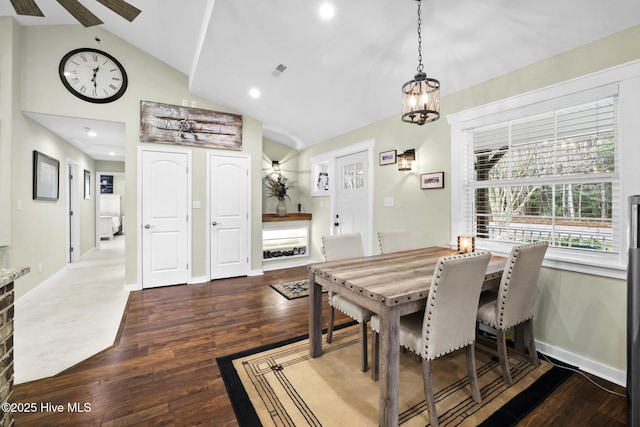 dining space with high vaulted ceiling, ceiling fan with notable chandelier, and dark hardwood / wood-style flooring