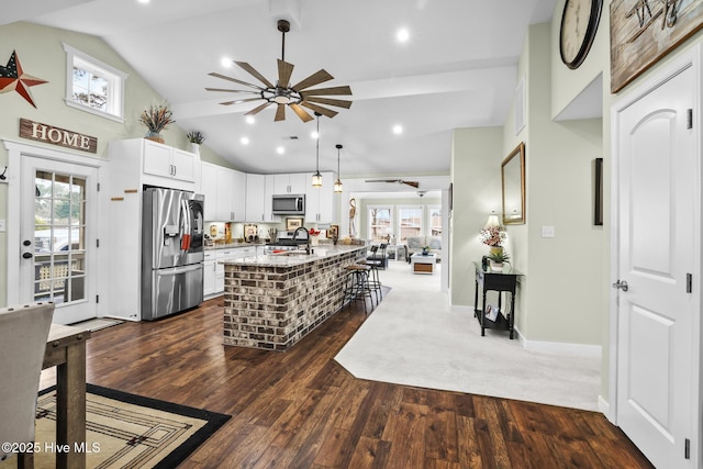 kitchen featuring a breakfast bar, appliances with stainless steel finishes, a center island, light stone countertops, and white cabinets