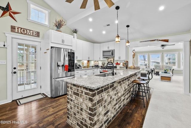 kitchen with sink, a breakfast bar, appliances with stainless steel finishes, white cabinetry, and light stone counters