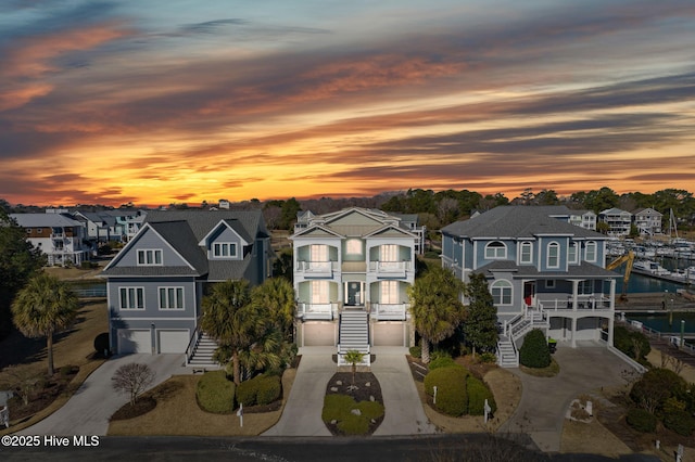 view of front of home featuring a balcony, driveway, an attached garage, stairs, and a residential view