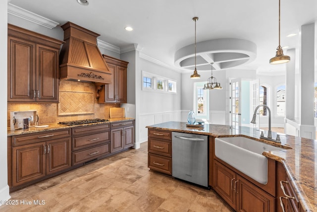 kitchen featuring premium range hood, a sink, gas stovetop, dishwasher, and hanging light fixtures