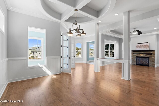 unfurnished living room with light wood-type flooring, a raised ceiling, a large fireplace, and stairs